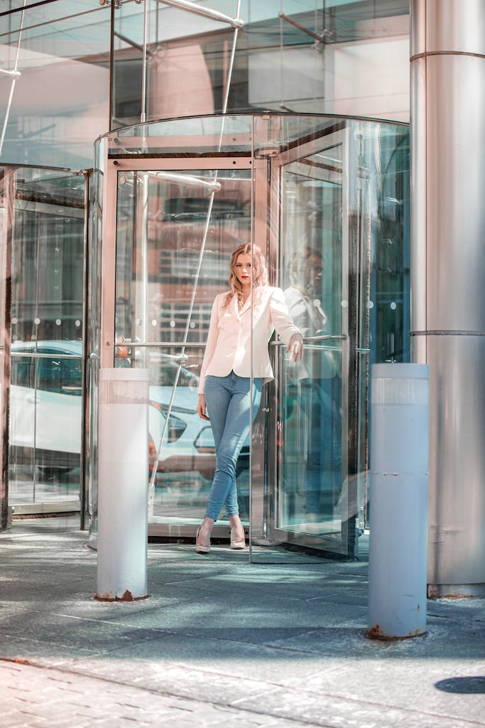 Woman in White Coat Standing Beside Glass Window